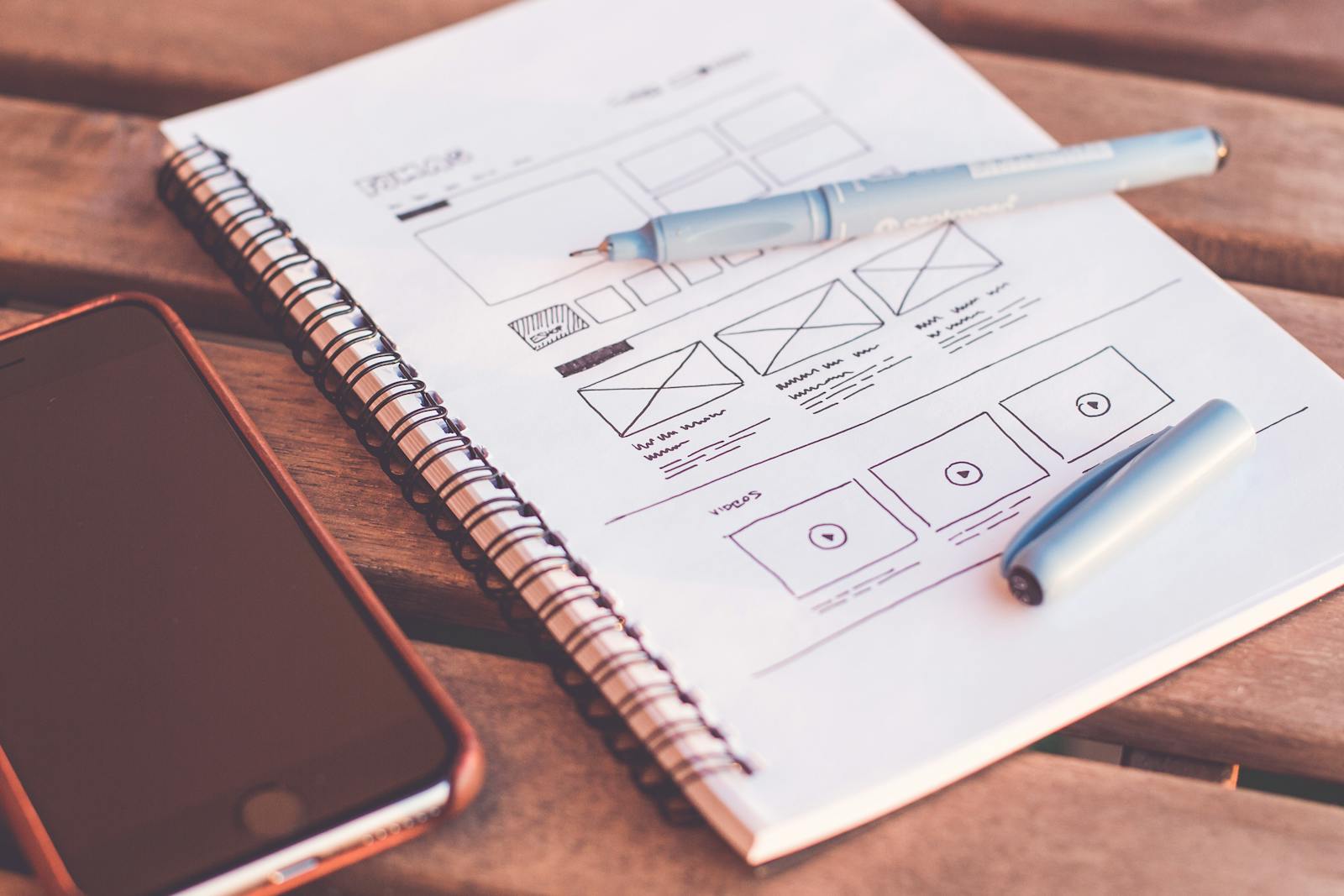 Calculator, laptop, and website wireframes on a desk representing website cost planning